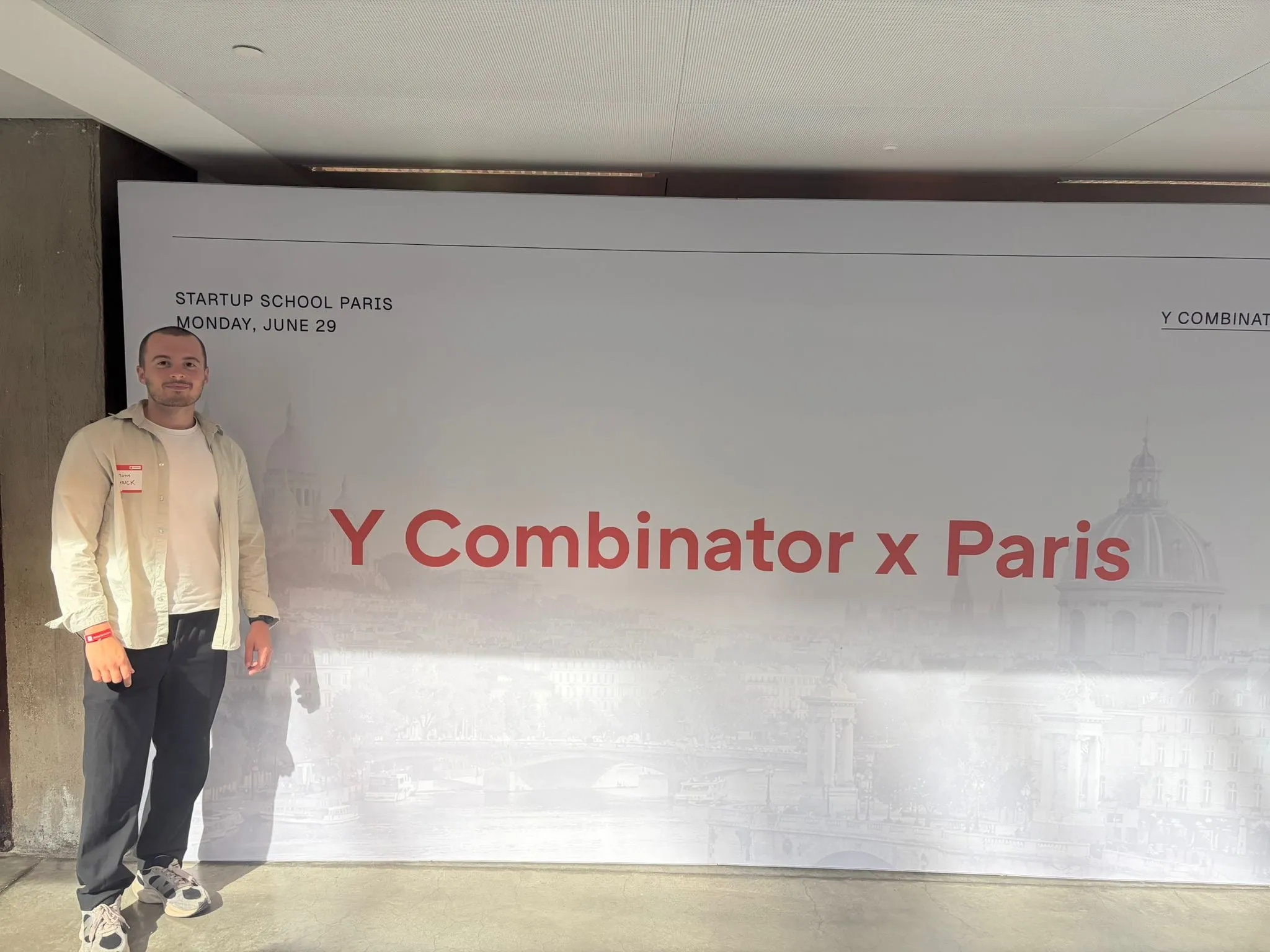 Tom Devynck standing in front of the Y Combinator x Paris backdrop at Startup School Paris